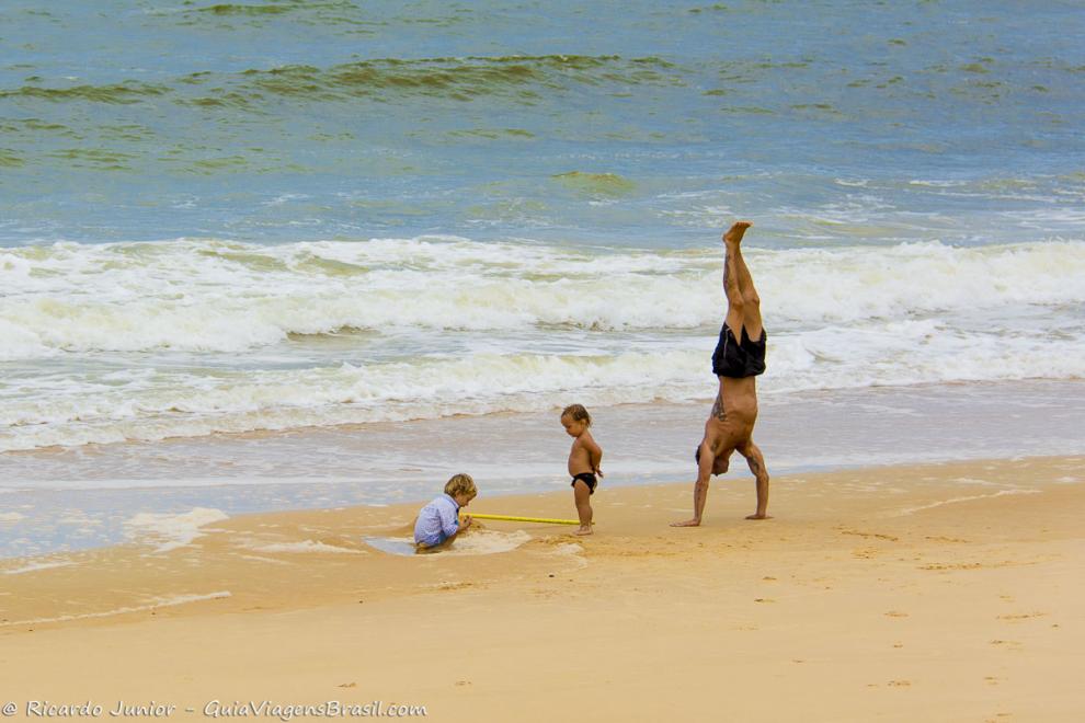 Imagem de um pai com duas criancas na beira da Praia de Caraiva.